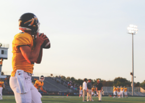 A football player in a yellow jersey getting ready to throw a football across a stadium